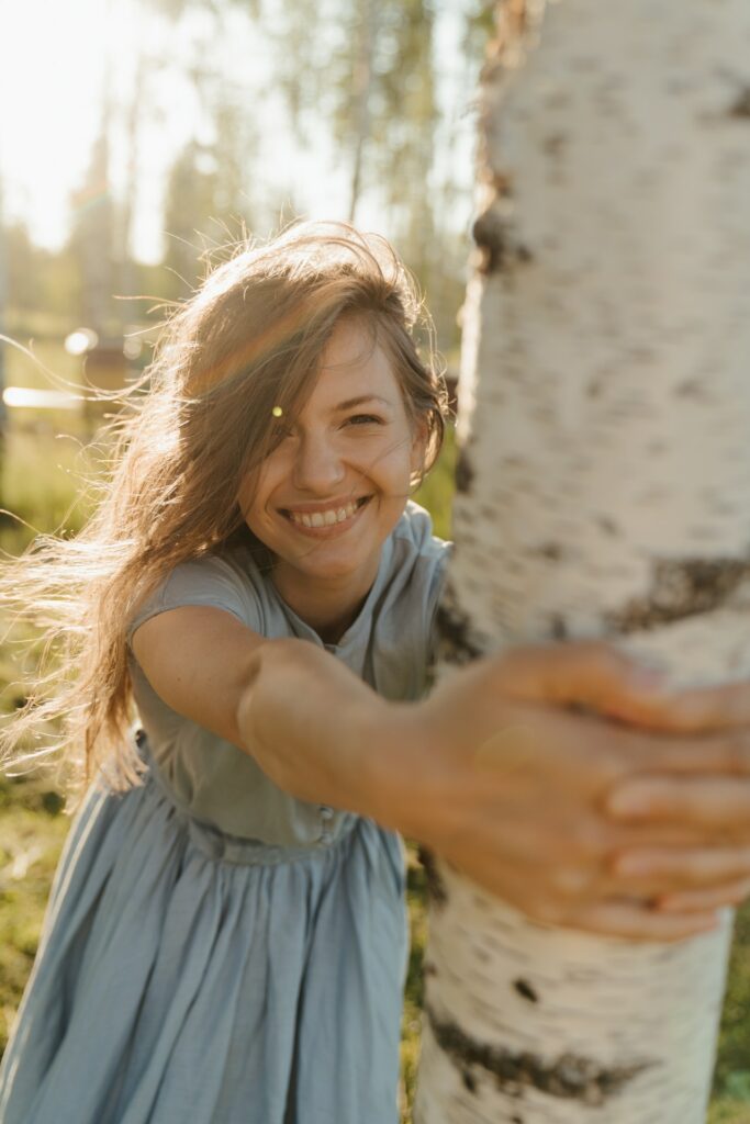 Junge Frau umarmt eine Birken. Es ist Frühling und sie ist glücklich und gesund