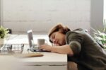 Erschöpfte Frau am Schreibtisch. Sie kann sich nicht konzentrieren und schläft am Bildschirm ein. Sie ist in einem Erschöpfungszustand