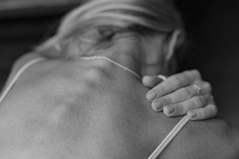 Frau hat einen Hautausschlag am Rücken durch Stress. Sie hat eine trockene und juckende Haut und kratzt sich daher. Stress hat bei ihr Hautjucken, trockene Haut und andere Hautprobleme ausgelöst